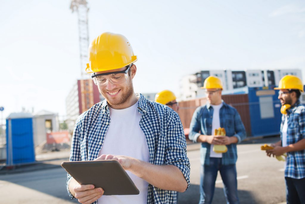 smiling builders in hardhats with tablet pc