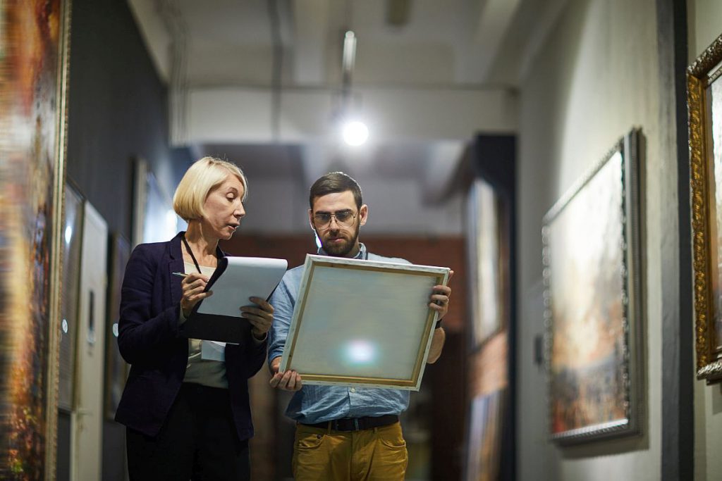 Portrait of two museum workers inspecting paintings; recent union drives concept