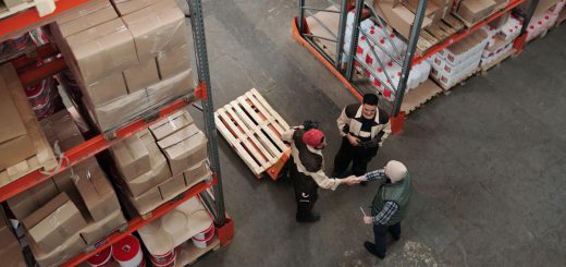Three workers in warehouse, two shaking hands; new union concept