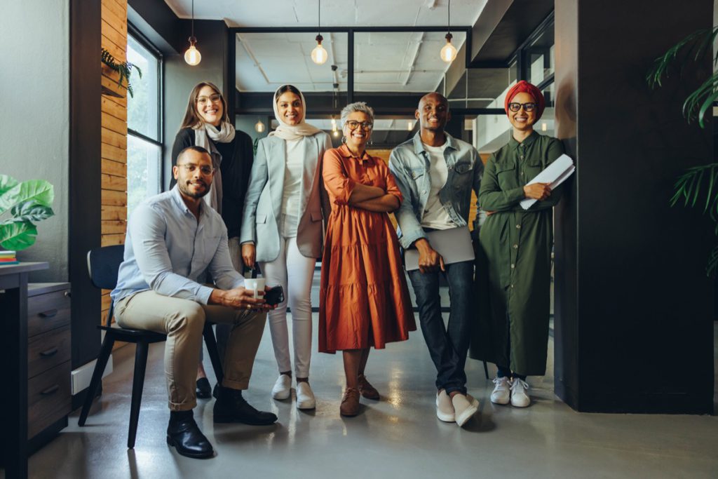 Multicultural business team smiling at the camera in an office; represent your workplace concept