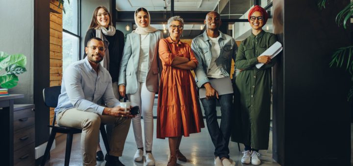 Multicultural business team smiling at the camera in an office; represent your workplace concept