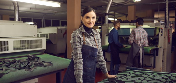female worker in machine shop smiling; Fair Contracts concept