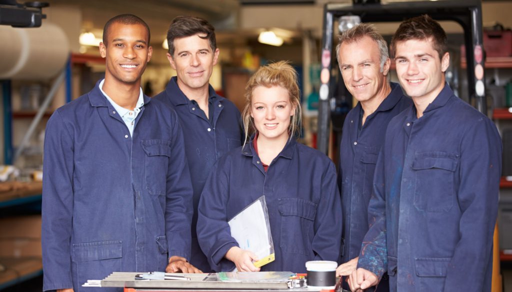 Group of smiling workers in plant; labor shortage in manufacturing industry concept